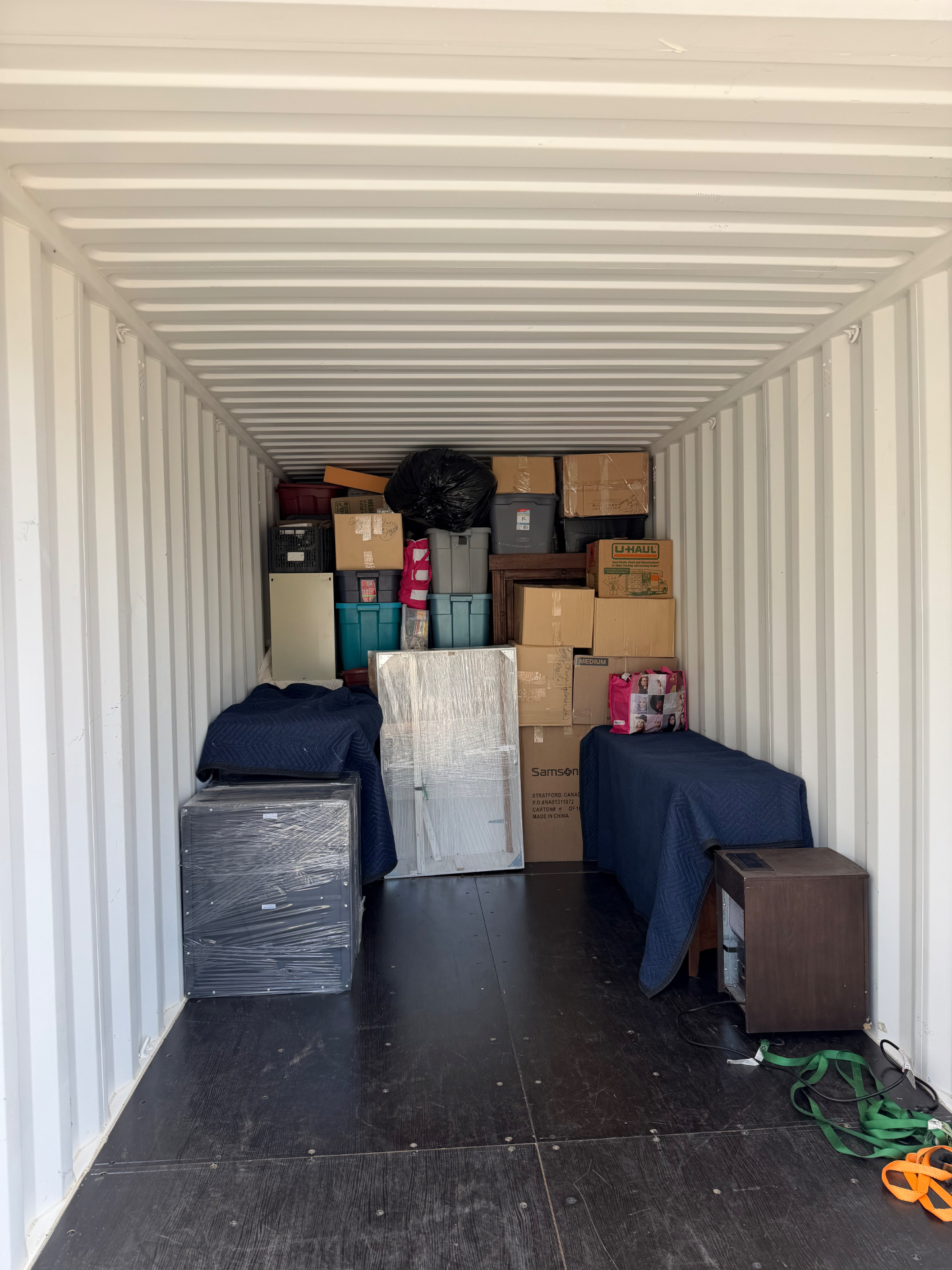 Neatly packed storage container with blanket-wrapped furniture and boxes